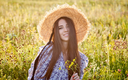 beautiful young girl with a straw hat in nature