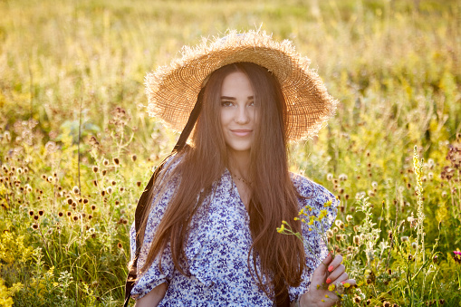 beautiful young girl with a straw hat in nature