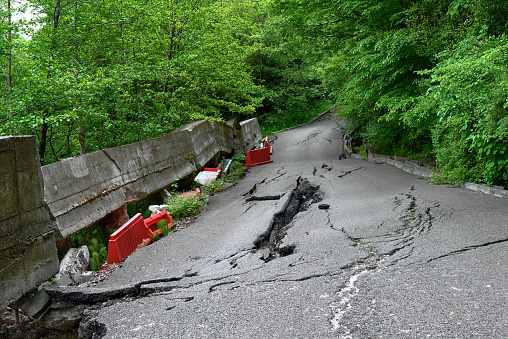 Destroyed road surface. As a result of the landslide, the asphalt collapsed. Cracks in the asphalt. Sochi, the road in front of the park yew-boxwood grove.