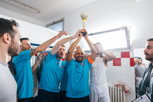 Group of male soccer players raising a trophy after winning the final match of the competition.