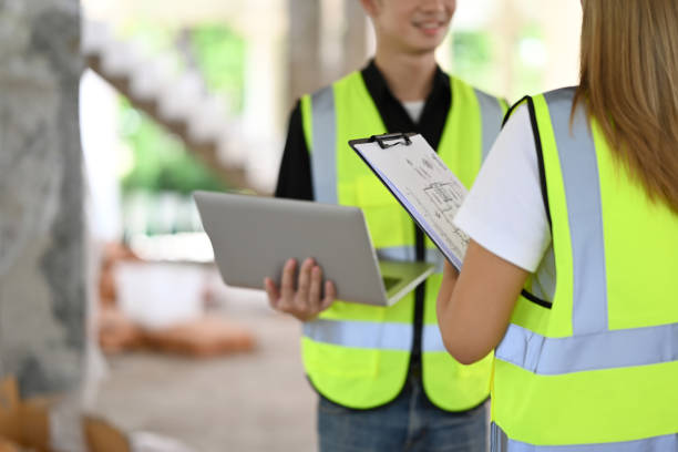 istock Two architects wearing uniform and safety helmet inspecting industrial building construction site. Industry, Engineer, construction concept. 1398948106