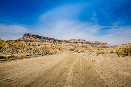 A dirt road runs through the desert and majestic mountainous areas of Baja California, in northern Mexico, near the Sea of Cortes.