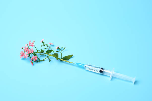 istock Syringe with pink flowers on blue background, beauty injections creative concept 1398950133