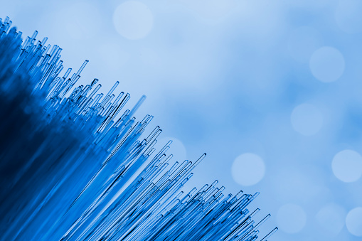A DSLR close-up photo of fiber optics on a blue defocused lights background. Beautiful bokeh. Space for copy.