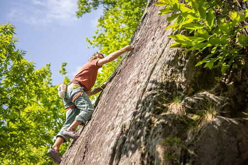 Rock climber hanging on vertical wall in the forest