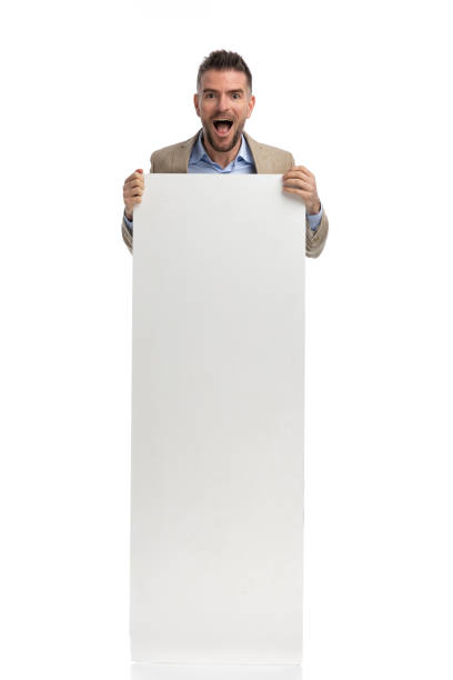 istock surprised businessman in suit hiding his body behind empty board 1398952601