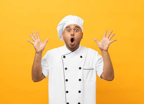 Wow excited face Young handsome asian man chef in uniform with hat standing posting looking camera on isolated. Cooking indian man Occupation chef People in kitchen restaurant and hotel.