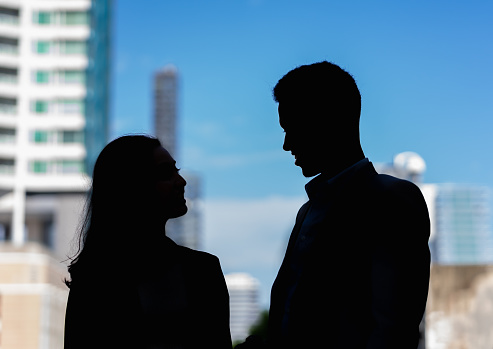 silhouette of woman and man happy talking together with building in city at background