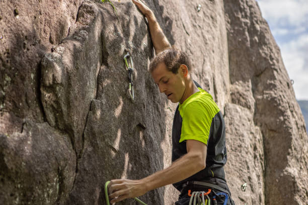 istock Man climbs steep rock face outdoors 1398954436