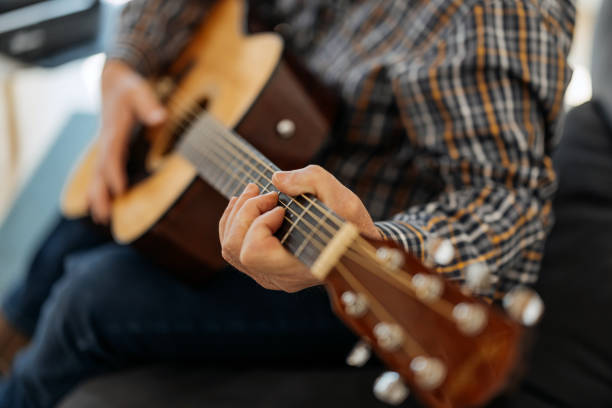 istock Senior man in casual clothes is smiling while playing guitar at home 1398955515