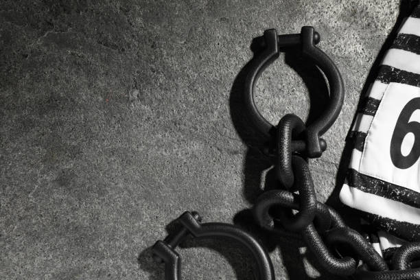 istock Steel shackles and jail clothes on grey table, flat lay. Space for text 1398955986