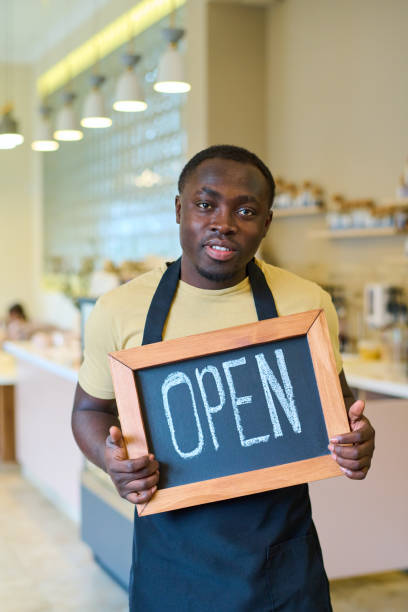istock Waiter with open sign standing in cafe 1398956831