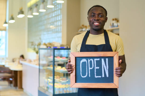 istock Waiter with open sign welcoming guests to cafe 1398956834