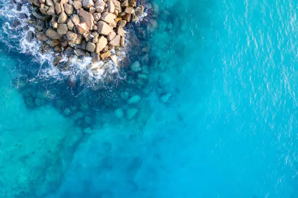 Aerial view of ocean wave reaching the jetty or breakwater at Fuvahmulah, a famous dive site in South Maldives. Summer diving and vacation travel concepts