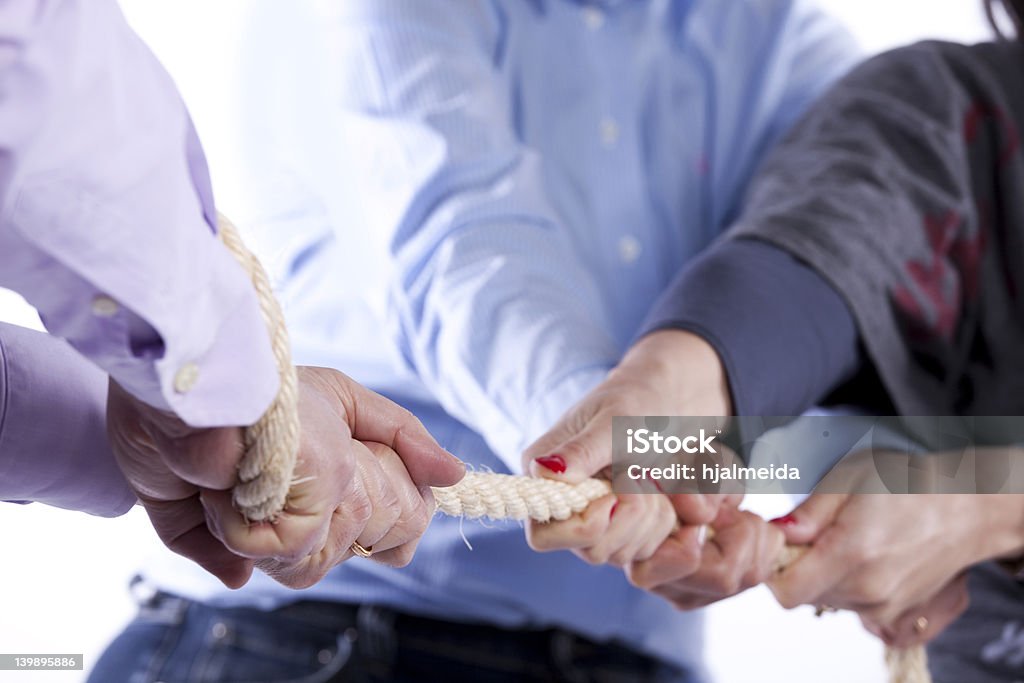 A game to tug-of-war between three people Group of woman hands pulling a rope competing with one man (selective focus) Conflict Stock Photo