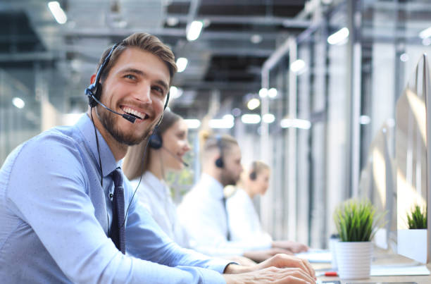 istock Portrait of call center worker accompanied by his team. Smiling customer support operator at work. 1398959546