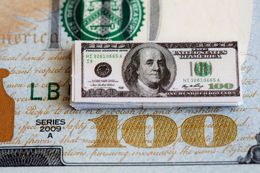 bundles of miniature 100 dollar banknotes on 100 dollar banknote background for design purpose