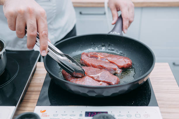 kochen von rinder-ribeye-steak in einer pfanne im kochkurs. steak mit gewürzen. kochprozess, nahaufnahme. - animal bone chop close up color image stock-fotos und bilder