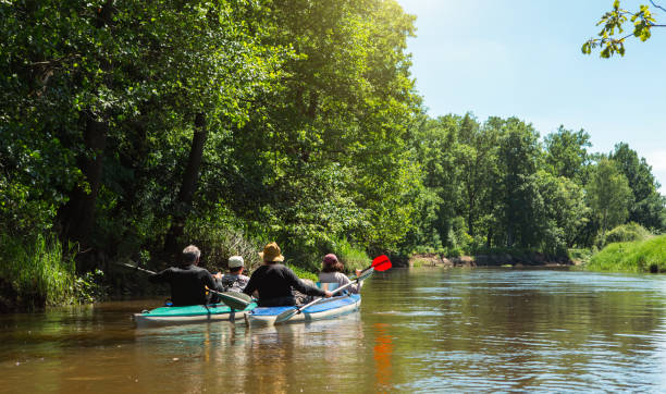 kajaktour mit der familie. mann und frau und älteres paar senior und seniora ruderboot auf dem fluss, eine wasserwanderung, ein sommerabenteuer. umweltfreundlicher und extremer tourismus, aktiver und gesunder lebensstil - doubles stock-fotos und bilder