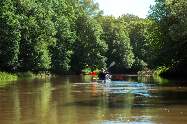 coppia di uomini e donne in barca a remi in kayak di famiglia sul fiume, un'escursione in acqua, un'avventura estiva. turismo ecologico ed estremo, stile di vita attivo e sano - canoeing canoe senior adult couple foto e immagini stock