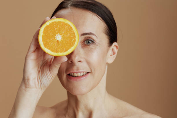 istock happy modern woman with orange on beige background 1398964230