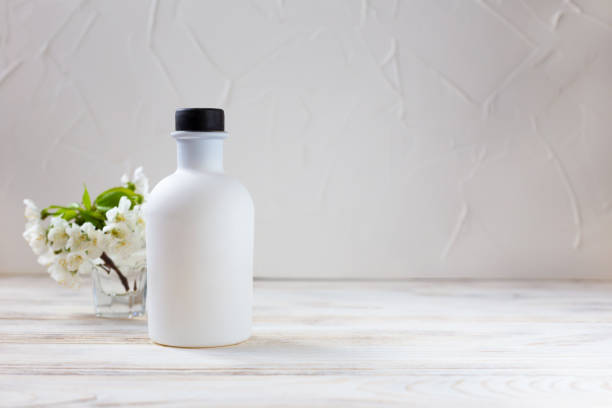 istock White bottle and flowers on a light background 1398965480