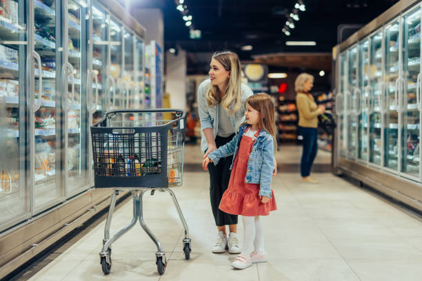 Young mom and her little daughter smiling and buying food stock photo
