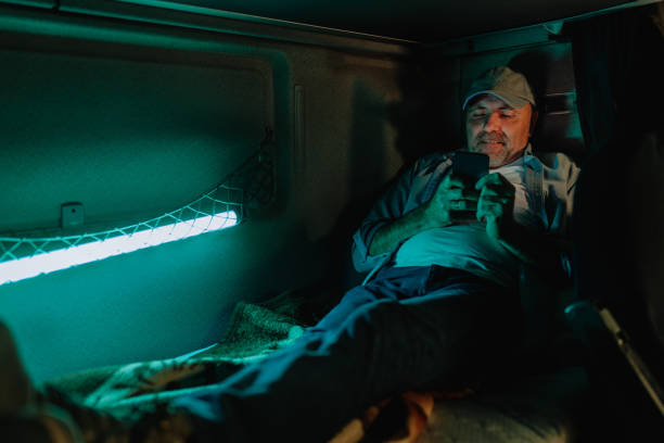 chauffeur de camion utilisant le téléphone avant de dormir en cabine - telephone cabin photos et images de collection