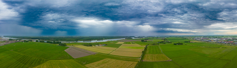 Incoming thunderstorm over fresh green meadows in the Melmerpolder and IJsseldelta region near Kampen in Overijssel, Netherlands during an overcast spring day.