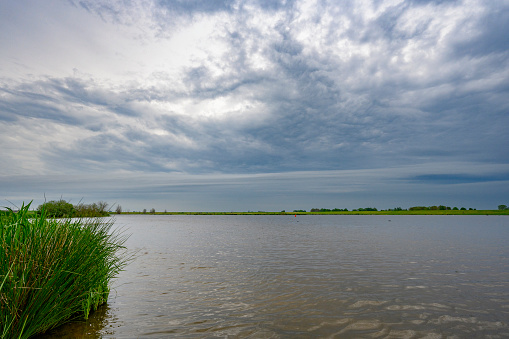 Storm clouds over the Reevediep waterway near Kampen in the IJsseldelta. The arcus clouds with thunder and lightning is moving fast over the green landscape.