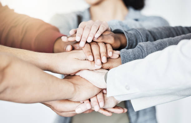 istock Group of businesspeople stacking their hands in support with their colleagues standing in a meeting in an office at work. Businesspeople piling their hands for motivation and success together 1398967662