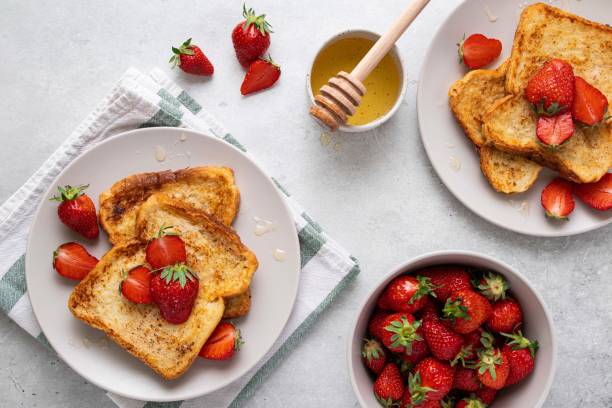 Traditional french toasts with strawberries and honey on grey background. Summer breakfast, brunch or lunch with berries. Top view. Traditional french toasts with strawberries and honey on grey background. Summer breakfast, brunch or lunch with berries. Top view. french toast stock pictures, royalty-free photos & images