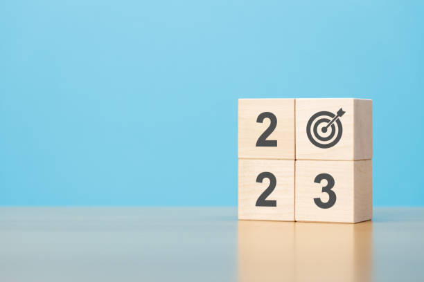 Wooden blocks with 2023 and target icon on wooden table blue background copy space.