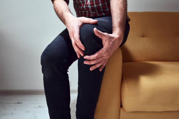 istock Man with injured knee at home. 1398968701