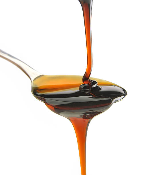 Maple syrup being poured onto a spoon and dripping off syrup being poured onto a spoon  honey jar liquid gourmet stock pictures, royalty-free photos & images