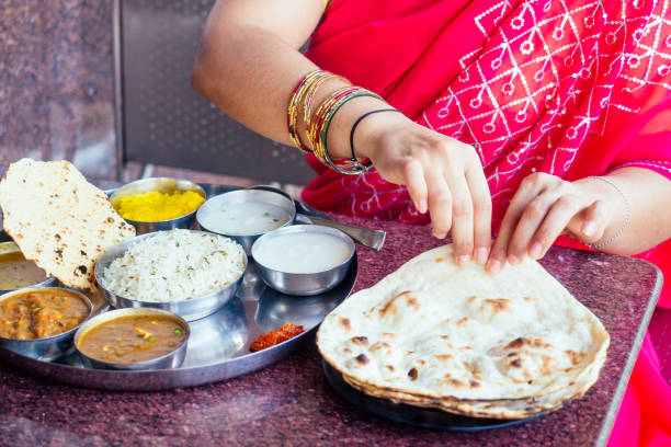 close-up foto de thali vegetariano tradicional indiano de arroz, dal, batatas, salada de tomate no prato de metal , mãos femininas roti índia tortilla chapati - asian cuisine horizontal spice restaurant - fotografias e filmes do acervo
