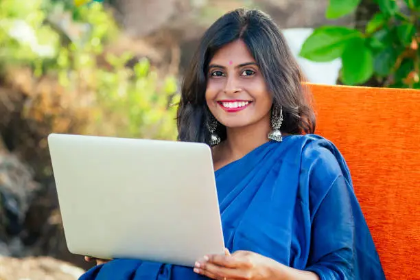 Photo of beautiful happy indian woman surfing laptop in tropical resort in Goa business vacation