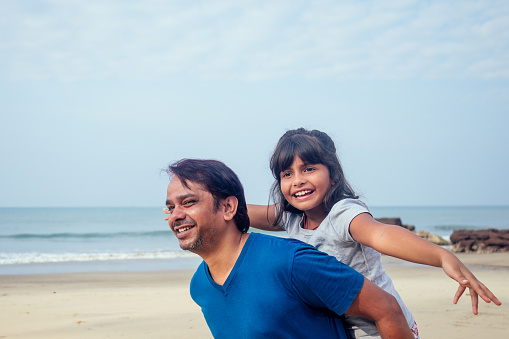 happy daughter and father having fun together in Goa .travel medical insurance concept.