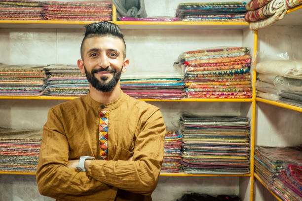 small shop owner indian man selling shawls at his store in arambol goa - nepal bazaar kathmandu textile imagens e fotografias de stock