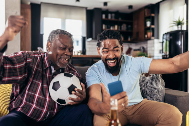 Man with senior father scream support favorite sports team together stock photo