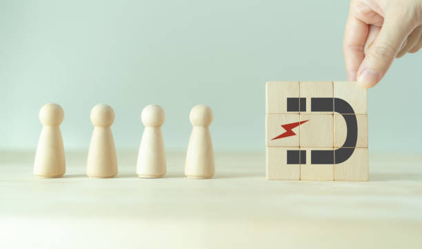 istock Digital inbound marketing strategy. Attracting potential customers. Customer retention concept. Putting wooden cubes with magnet attracts customer icons on smart grey background and copy space. 1398971990