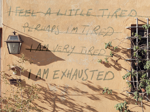 Several messages about tiredness and personal exhaustion are written on a residential wall in series. *** The text was digitally superimposed and a release is provided ***