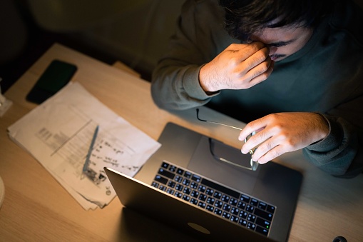 Asian businessman low income man checking his home finances and looking worried while looking at the utility bills at night.