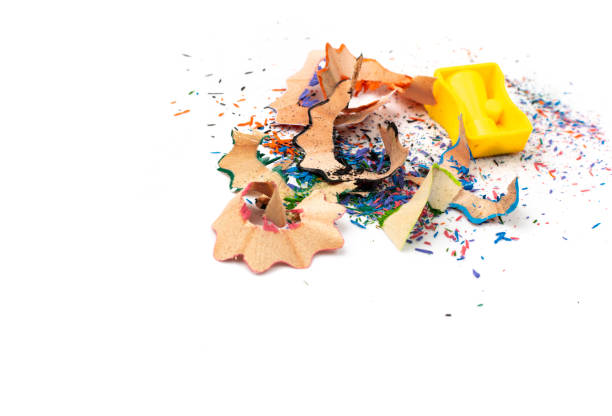Color wood pencil shavings with pencil sharpener isolated. Vintage pencils shavings, organic waste, wooden cutting peel on a white background