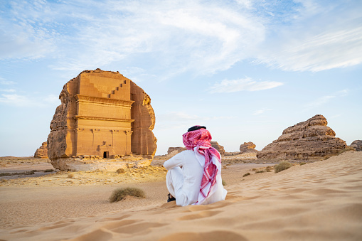 Hombre saudí local visitando Hegra y arquitectura excavada en la roca photo