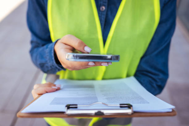 tiro cortado de um empreiteiro irreconhecível sozinho no armazém e usando uma calculadora durante a tomada de estoque - inspector clipboard businesswoman white collar worker - fotografias e filmes do acervo