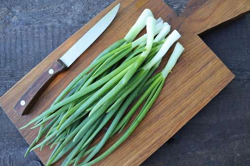 Top view of spring onions bunch ready to cutting on chopping board .