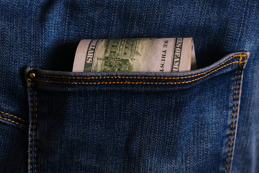 Jeans pocket with money, close-up. Blue jeans pocket with hundred dollars banknotes
