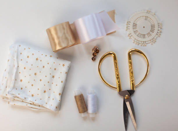 istock The layout of sewing accessories and fabric on a white background. Sewing threads, needles, fabric, buttons and scissors in gold and white. top view, flatlay 1398984418
