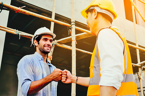 Construction engineer and worker at construction site, join hand together concept